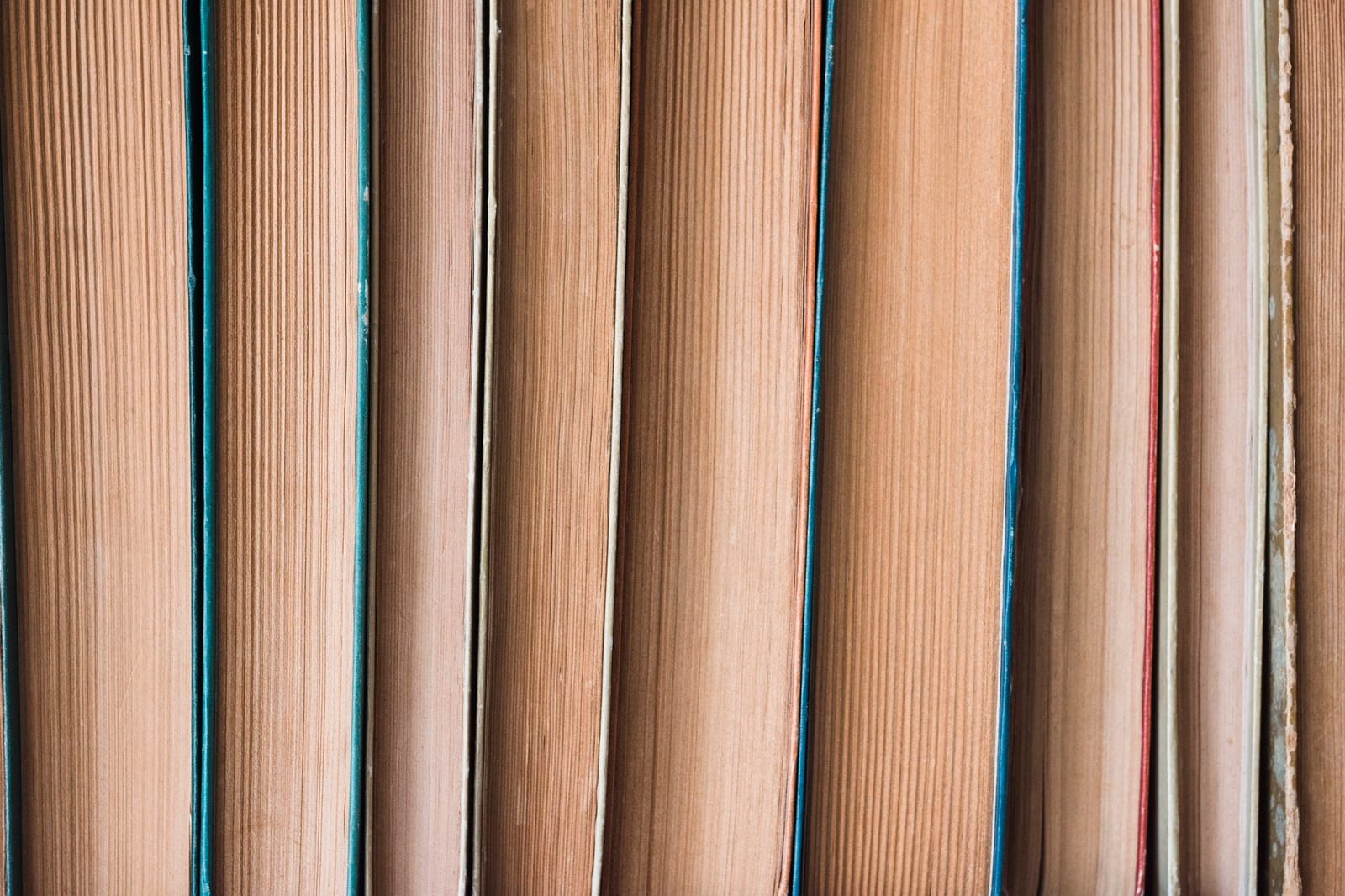 Detalhe aproximado das páginas e lombadas de vários livros lado a lado.